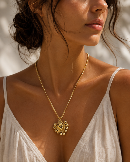 Collar corazón sagrado dorado en modelo con vestido blanco